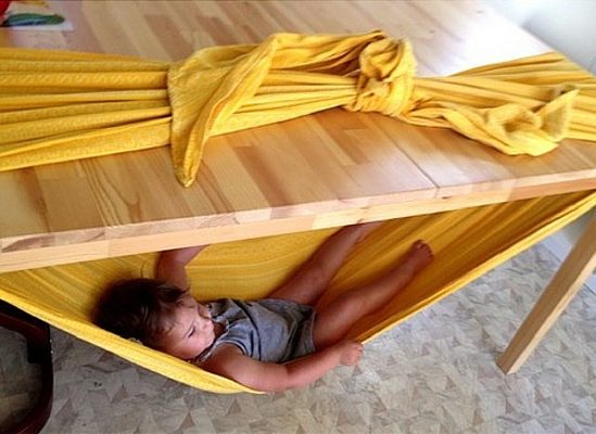 All you need is strong sheet and a table to make a baby-friendly indoor hammock.