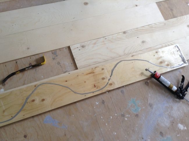 It's gluing time! He used a construction-grade adhesive to glue each board to the subfloor.