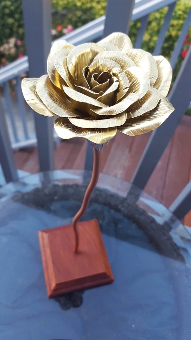 He mounted his rose that would never wilt on a redwood base.