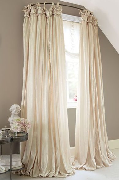 Hang drapes on curved shower curtain rods to get the look of bay windows.