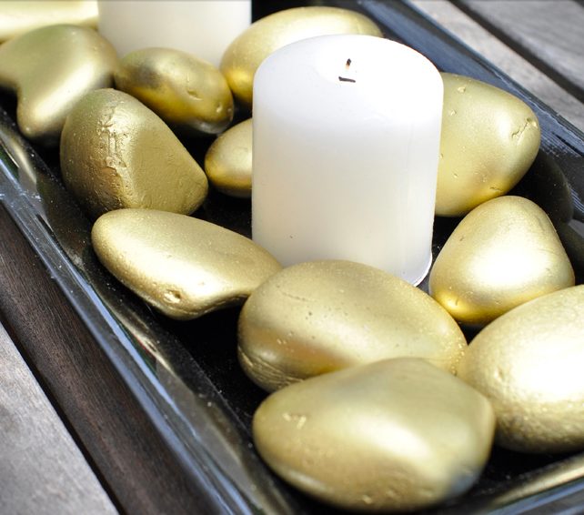 Steal a few landscaping pebbles that your neighbor probably paid good money for, whip out some spray paint, and make everyone jealous of your <a href="http://club.chicacircle.com/gold-rock-candle-centerpiece/" target="_blank">chic centerpiece</a>.
