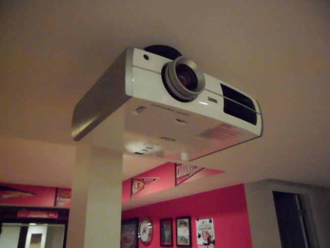 After cutting a few holes in the ceiling to run the wires, he hung the projector. 