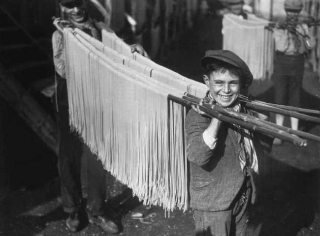 This little boy sure loves his job carrying around pasta at this Italian pasta factory. 