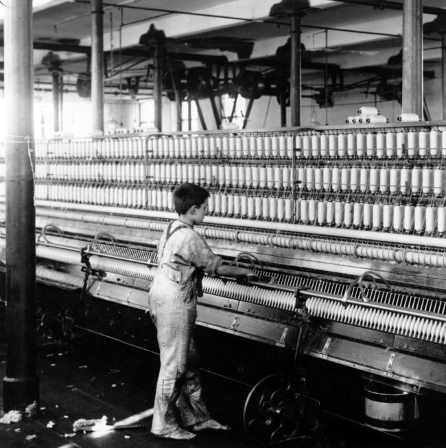 Child labor laws weren't always a thing. This young boy is in the middle of mule spinning at a cotton mill in Manchester, England.