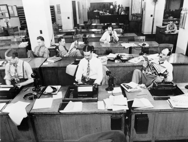 Newsroom of the New York Times newspaper in 1942. Reporters and rewrite men can be seen working on stories for the next day's paper. The rewrite man in the background is receiving a story on the phone from a reporter in the field.
