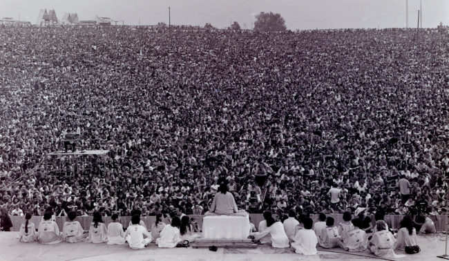 Massive crowds gather as Swami Satchidananda gives the opening speech at Woodstock in 1969.