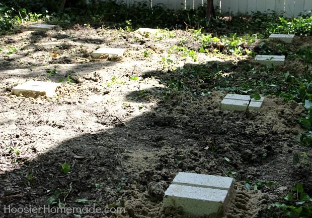 Needing a base for the pallets, Liz dug holes for concrete blocks.