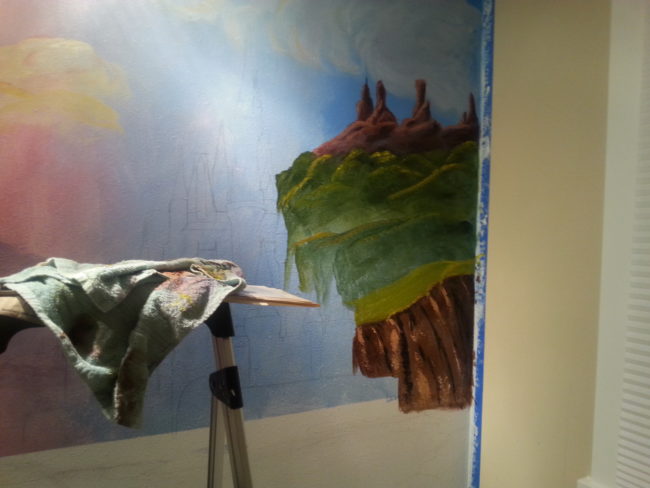 She wanted to add the other scenery before painting the castle, so she began with the cliffs.