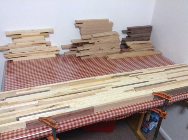 After sawing the wood into smaller strips and stacking them, he began laying out the tabletop.