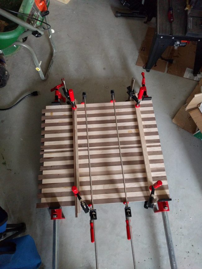 He glued the strips to make two separate boards and clamped them while they dried.