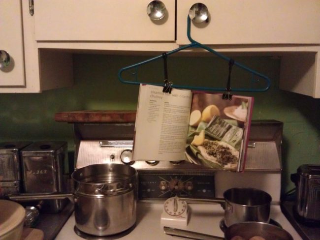 For easy cookbook reference, attach two hair ties to a clothes hanger and thread them through two binder clips for added tension.  Hang it up and you're good to go!