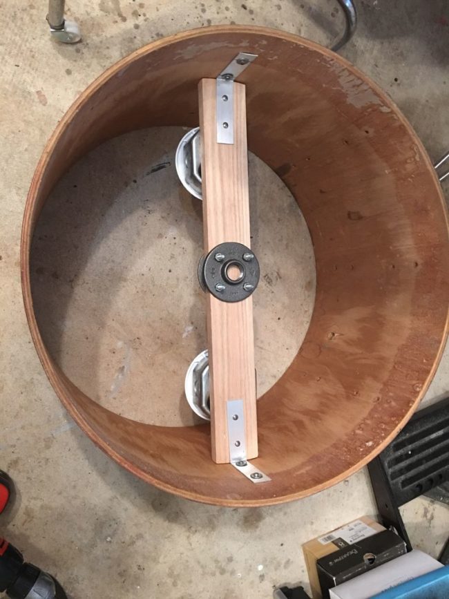 Next, he drilled pipe flanges to a board and attached them to the drum using L-brackets.