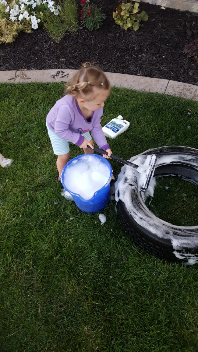 With the help of this cutie, he used soap and degreaser to scrub an old tire clean.