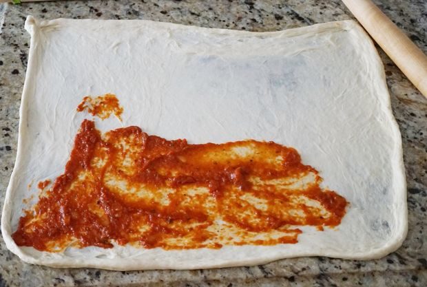 She began by rolling out some pre-made pizza dough and lathering on the pizza sauce.
