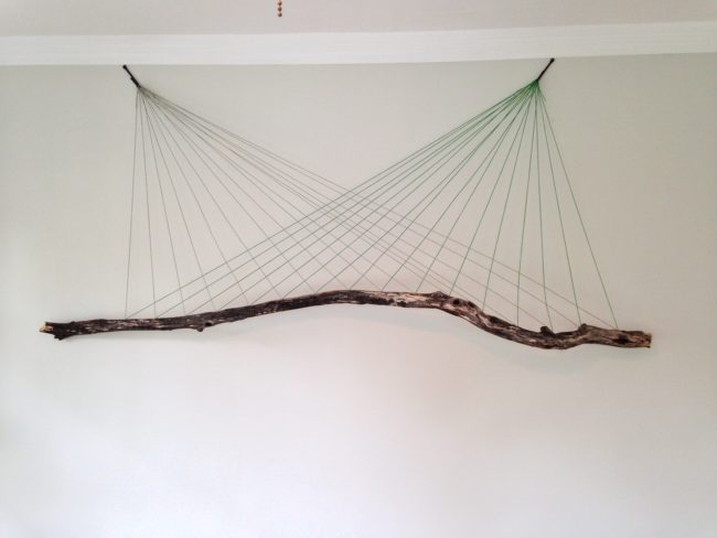 Next, she attached two hooks to the wall and tied the ends of the strings to each side in a criss-cross pattern.