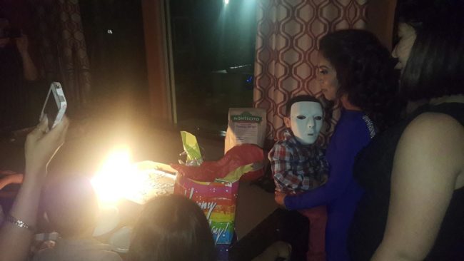Sure, the birthday boy may have lit the entire cake on fire, but what's up with the child in the mask?