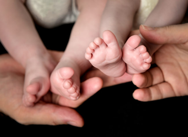 Some commenters have suggested that the parents tattoo a small dot on the bottom of one of the baby's feet. The bottom of the foot is not only one of the least painful spots to get a tattoo, but typically wears off after several years. By that time, the boys would be old enough to identify themselves. 