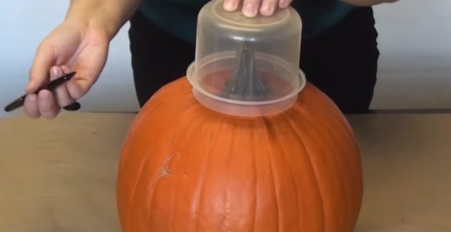 Begin by tracing a hole around the stem of your pumpkin using your plastic container. 