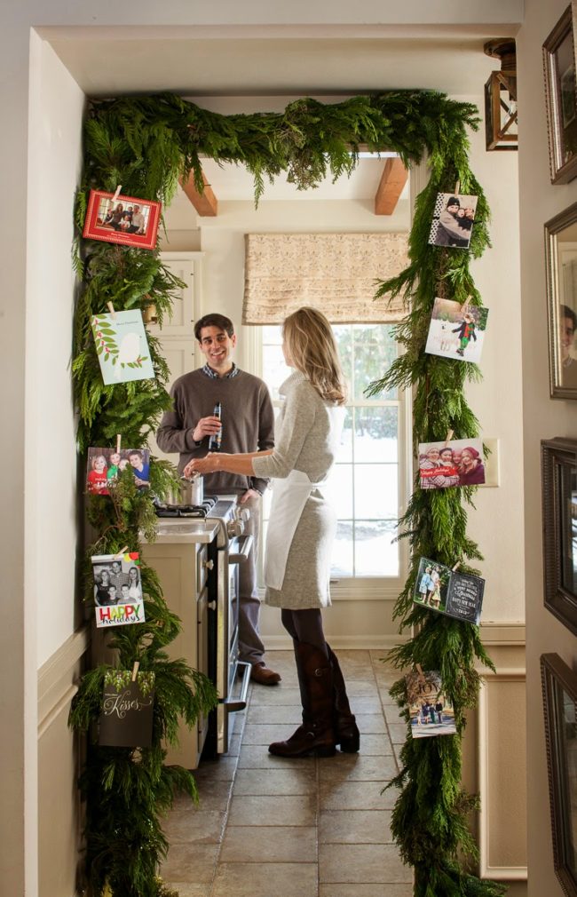 <a href="http://www.nineandsixteen.com/2014/11/midwest-living-magazine-our-christmas.html" target="_blank">Frame a doorway</a> with fresh or fake garland, then use clothespins to attach holiday cards.